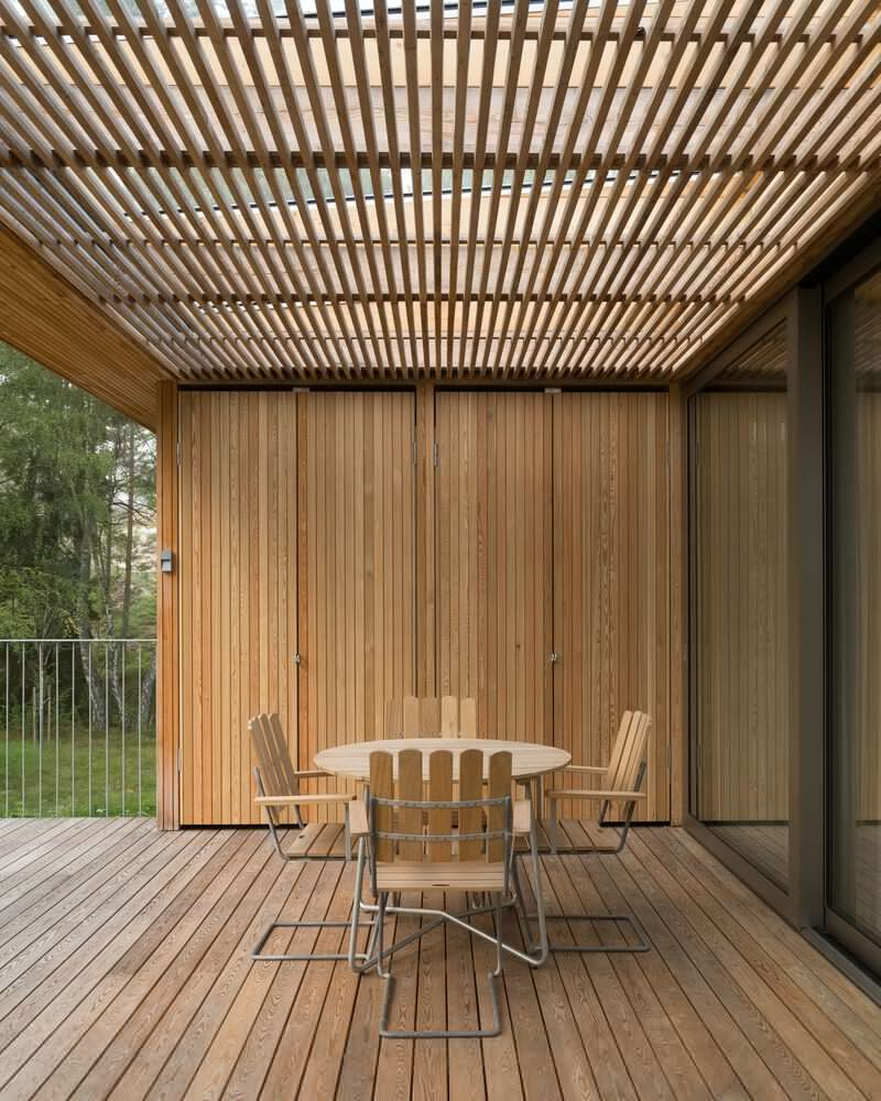 Covered deck with slatted timber pergola overhead and outdoor dining furniture on wood decking