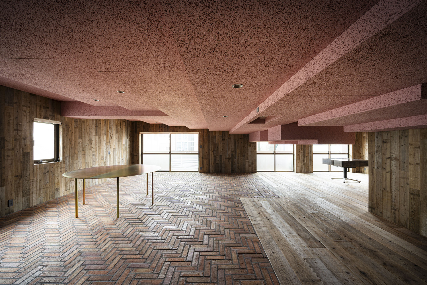Interior room with herringbone wood flooring, timber plank walls, pink textured ceiling and exposed beams
