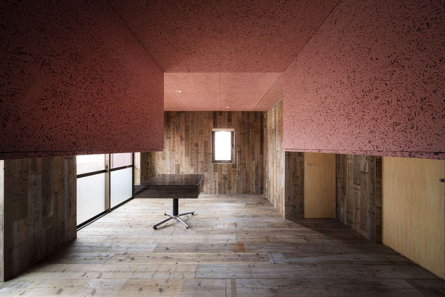 Small room with weathered timber walls, arched doorway, pink cork ceiling and timber floor