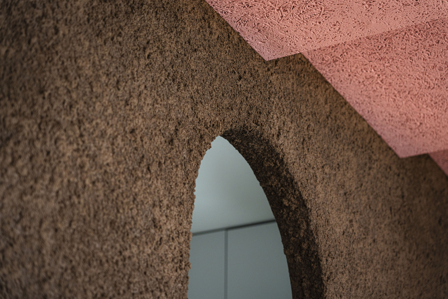 Close-up of arched opening cut through brown and pink textured wall surfaces