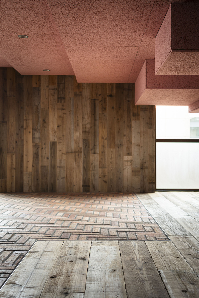 Corner detail where herringbone brick floor transitions to timber planks beneath pink cork ceiling panels