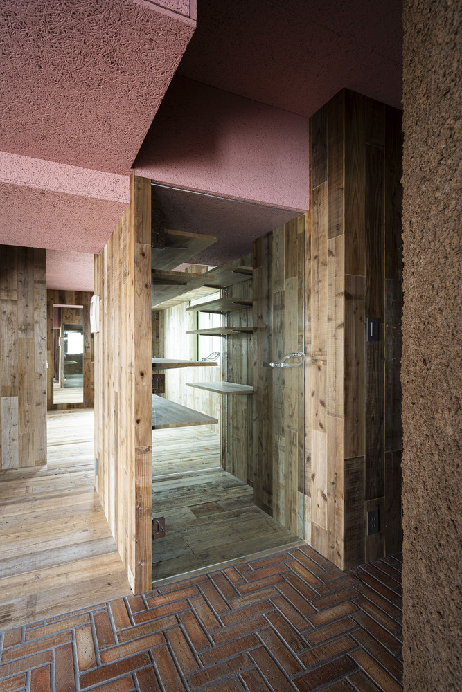 Timber-framed doorway opening onto herringbone brick floor with pink ceiling above