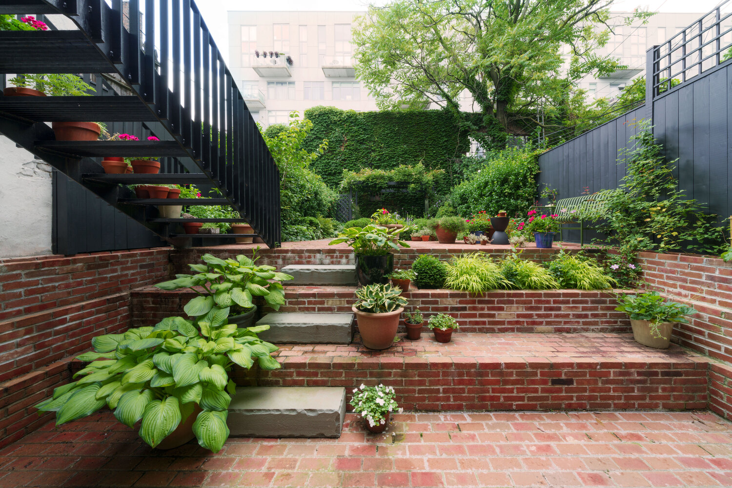 Stepped brick terraces with stone treads and hostas leading through planted courtyard garden