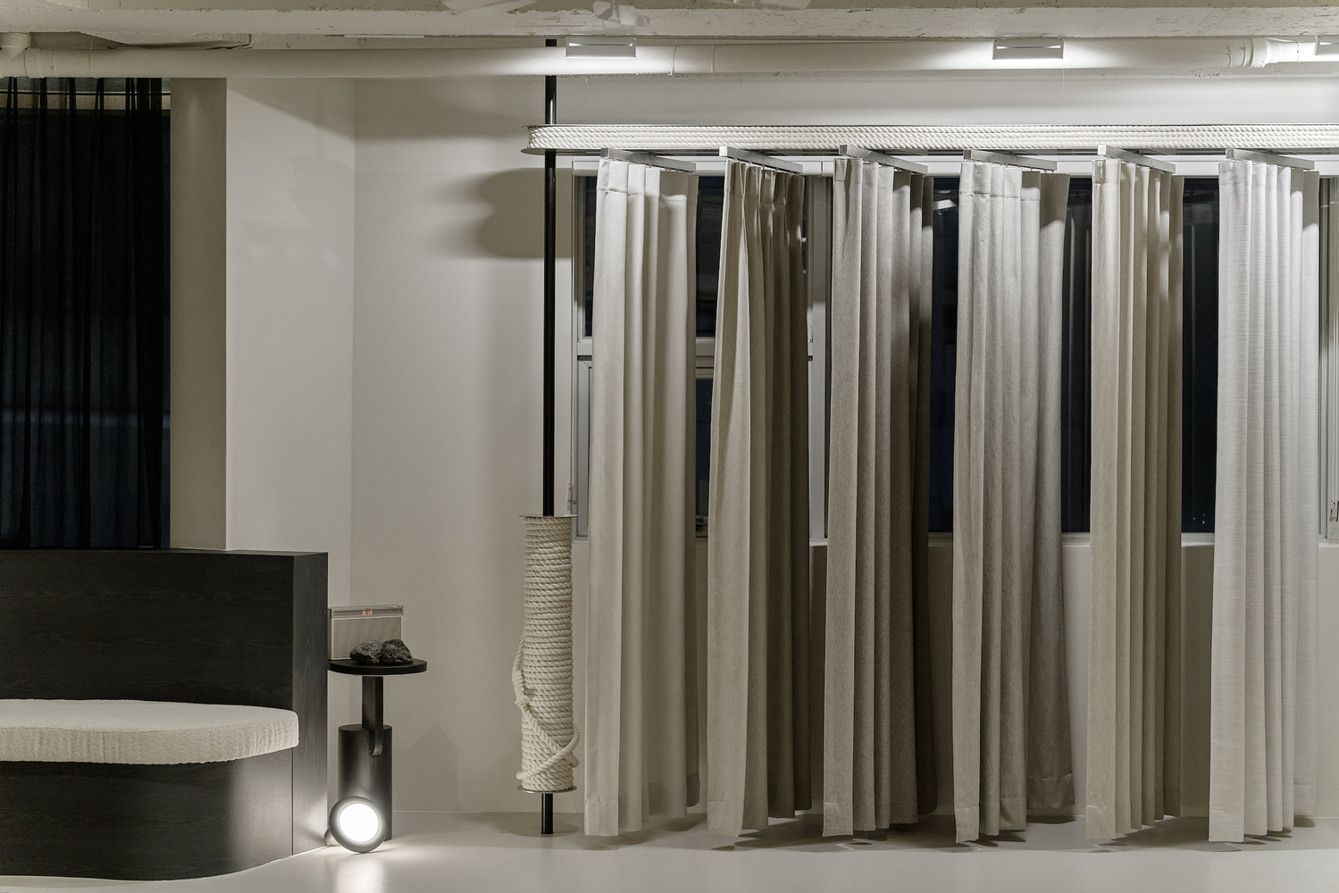 Fitting room enclosures with floor-to-ceiling curtains in neutral tones and black frames