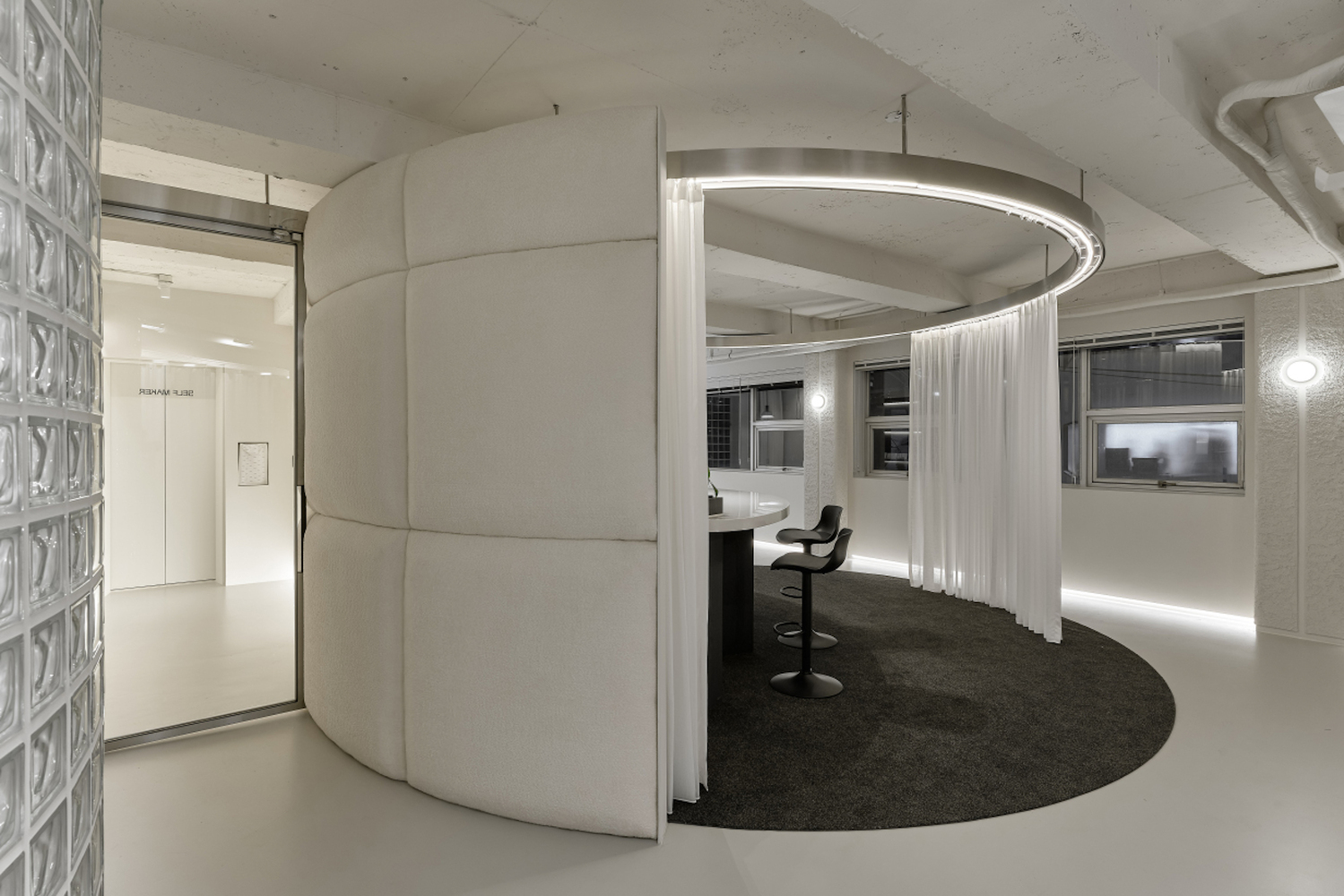 Curved corridor with circular curtain enclosure and glass block wall at left