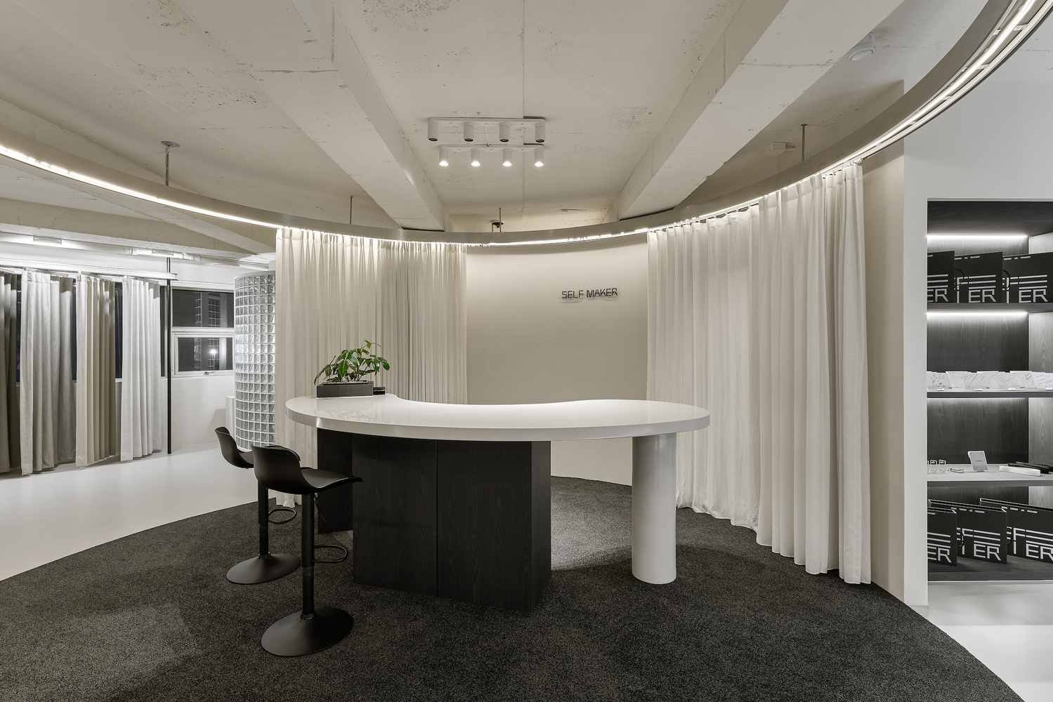 White elliptical table on dark carpet surrounded by flowing curtain and illuminated perimeter band