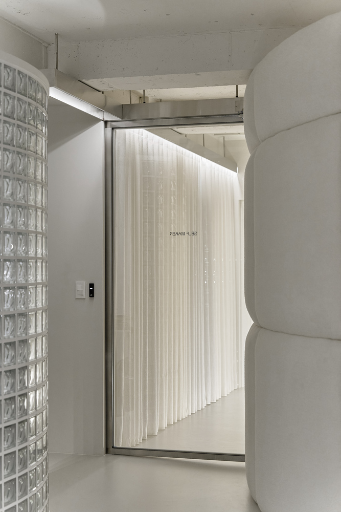 Glass block wall beside a framed doorway with backlit pleated curtain screen