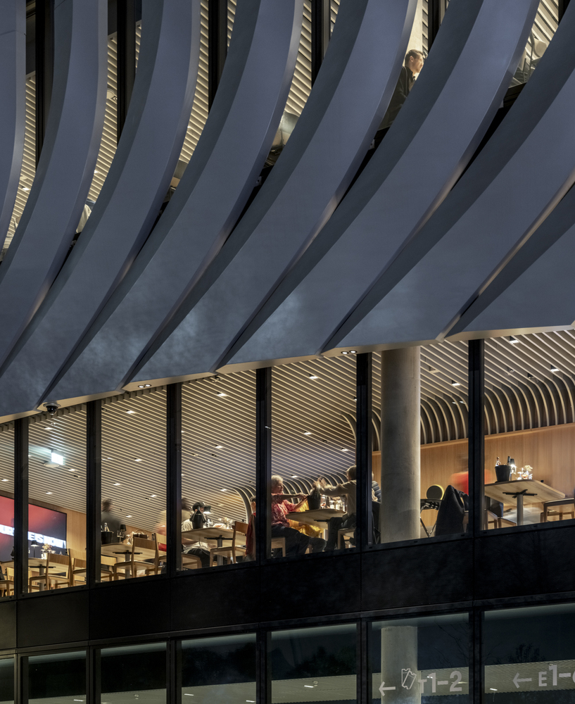 Close-up of the vertical fins meeting the glazed facade at dusk with interior lighting visible