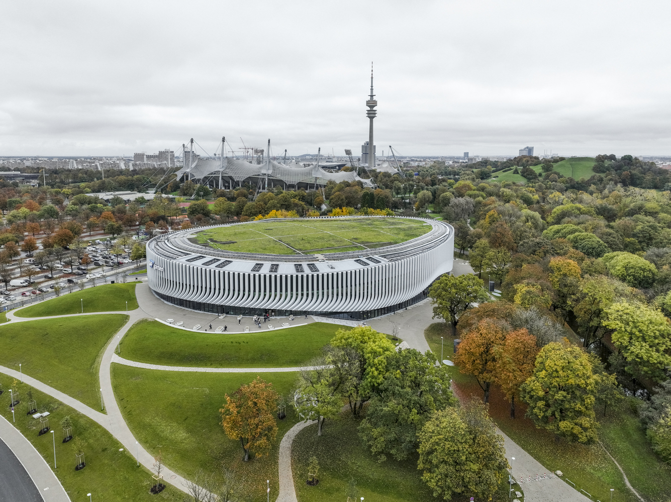 Elevated view of the oval roof with seating terraces surrounded by autumn foliage and park pathways