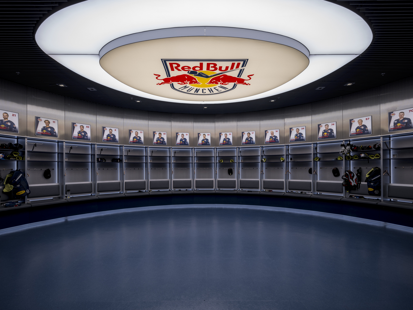 Circular locker room with individual player stalls beneath a large glowing disc ceiling fixture