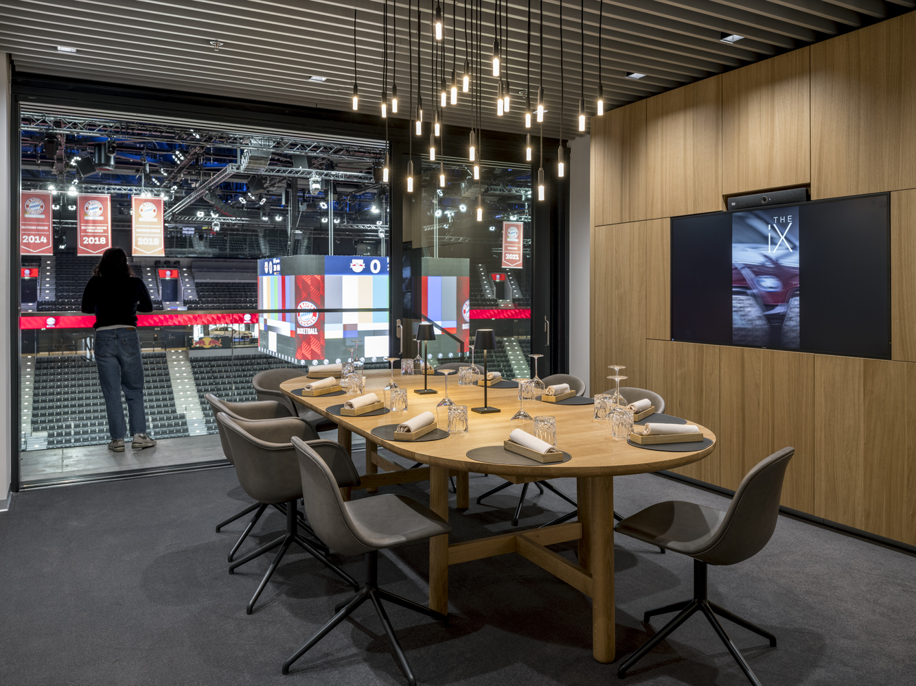 Private dining suite with oval timber table and pendant lights overlooking the arena seating bowl