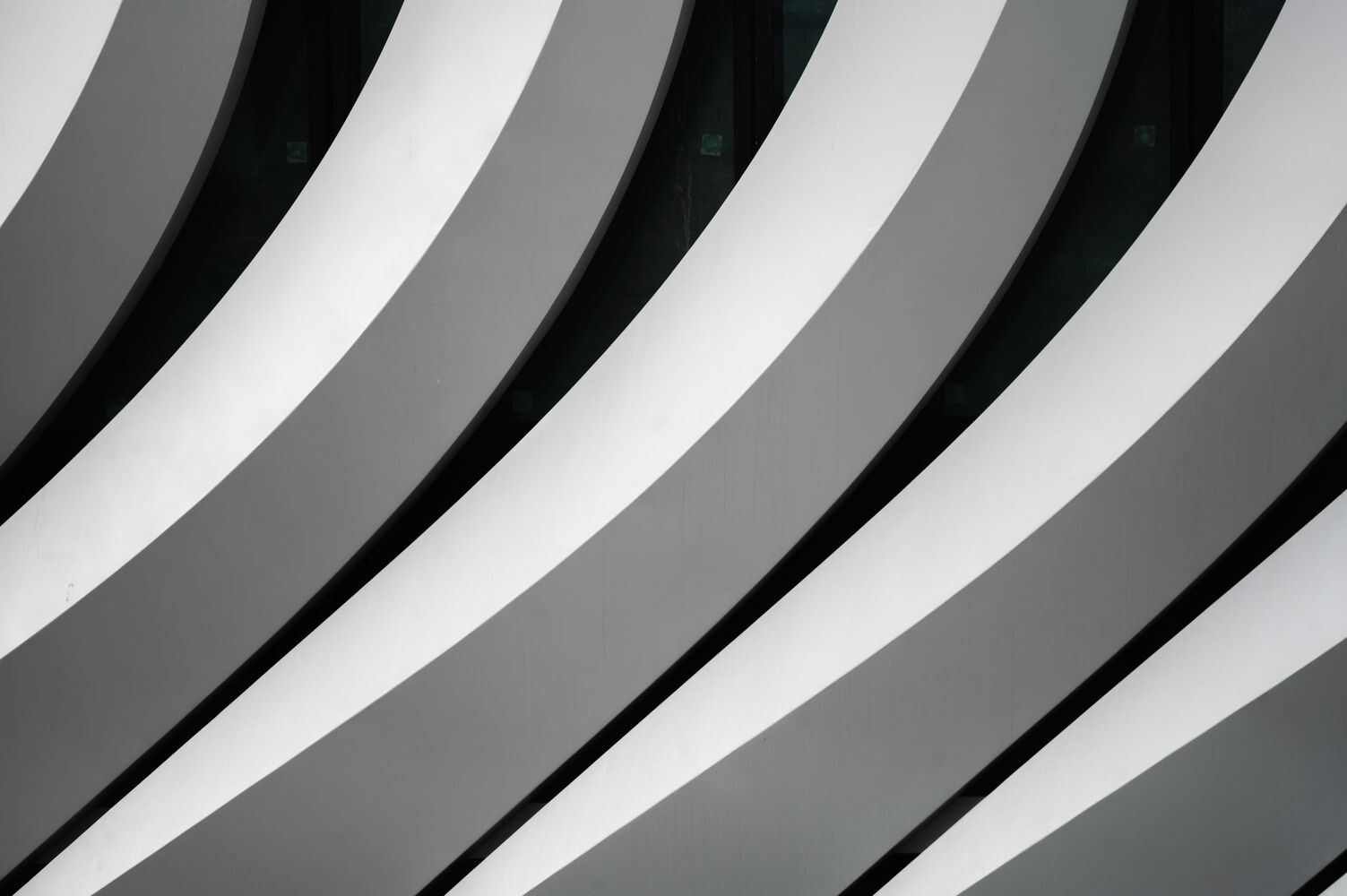Upward view of diagonal white and grey facade fins creating alternating shadow patterns