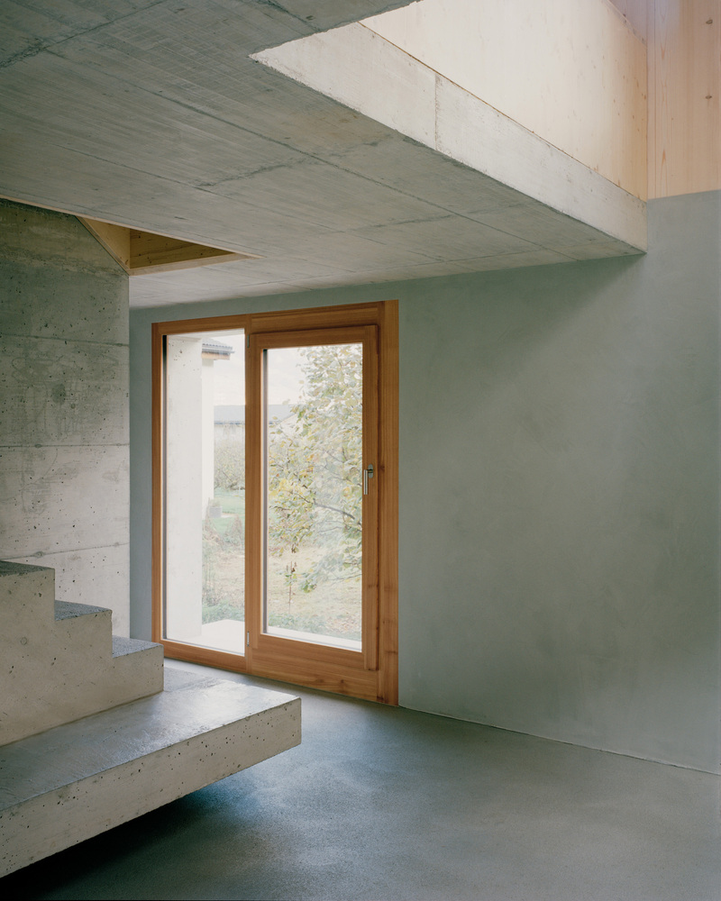 Concrete cantilever above a timber-framed door with cantilevered concrete stairs in soft daylight