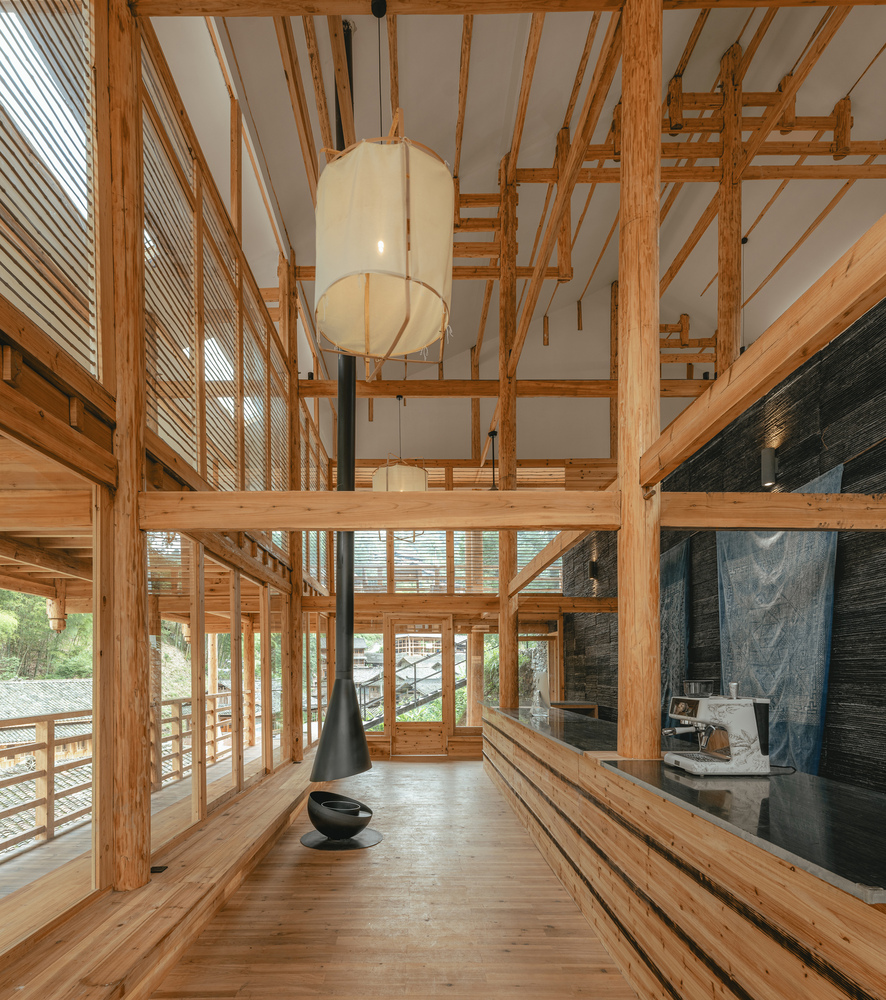 Double-height interior with exposed timber framing and a pendant lantern above a fireplace