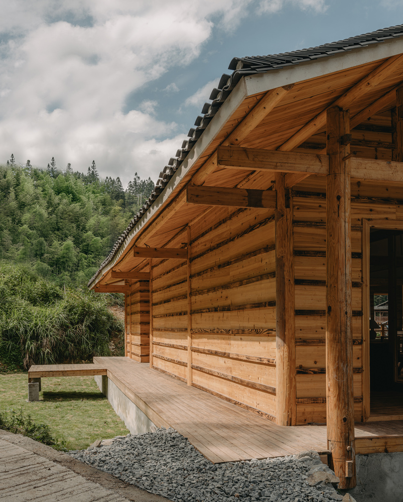 Exterior corner showing horizontal timber cladding and exposed rafter eaves beneath a tiled roof