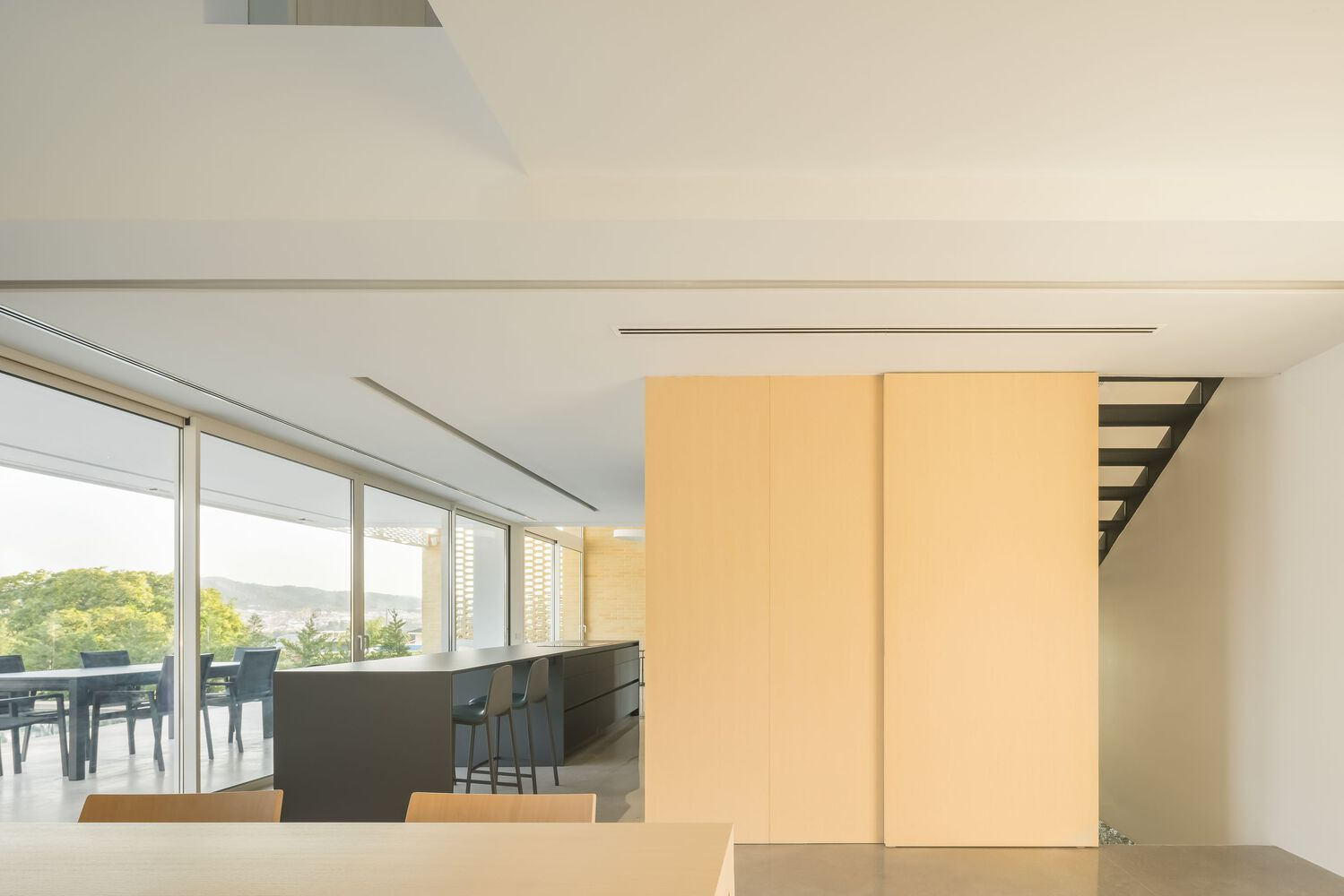 Open-plan dining and kitchen area with timber sliding panels and glimpse of staircase
