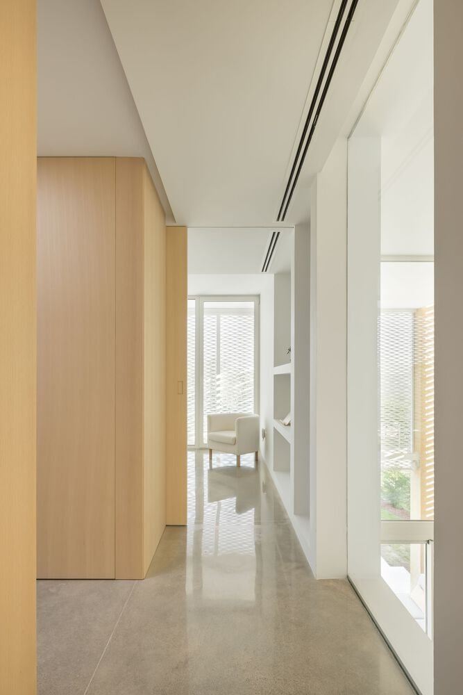 Hallway with blonde wood cabinetry and flush-glazed window overlooking perforated screen