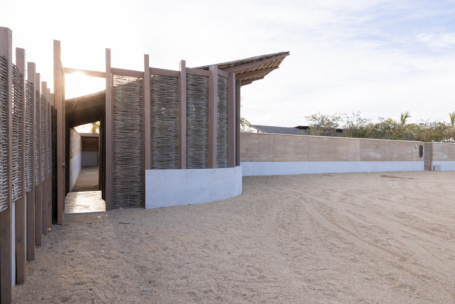Pavilion with slatted timber screens on white plinth base and angled roof at sunset