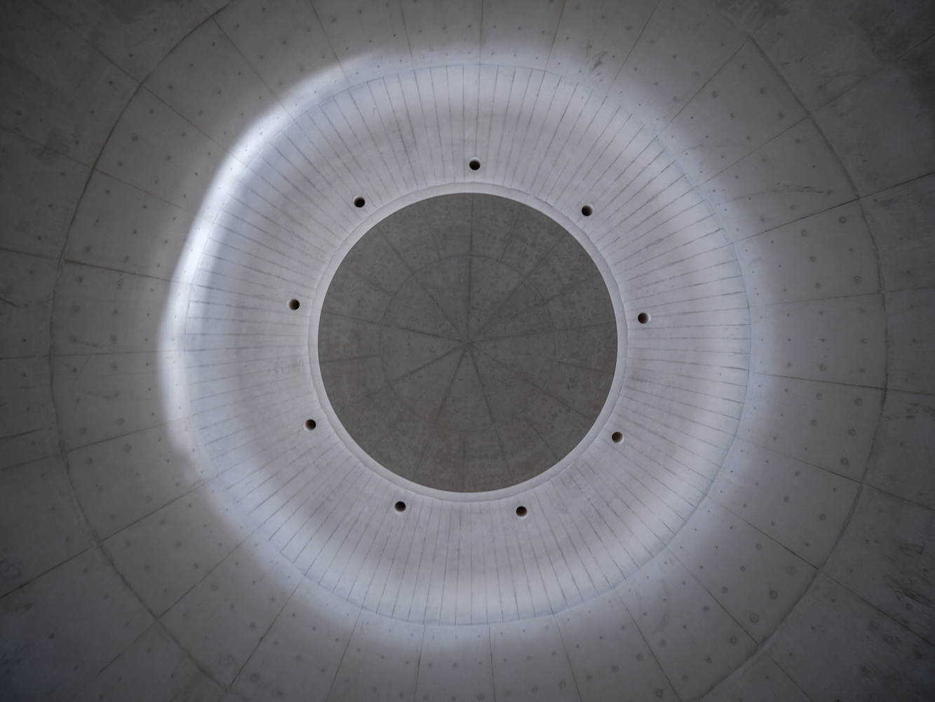 Looking up at circular oculus with concealed perimeter lighting in concrete dome