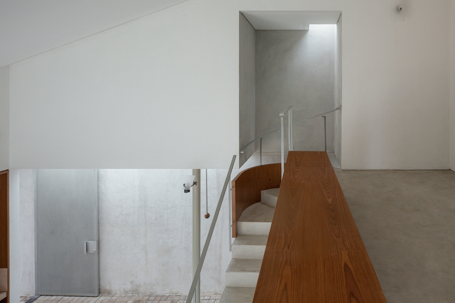Upper level landing with glass guardrail and timber-clad volume overlooking the floor below