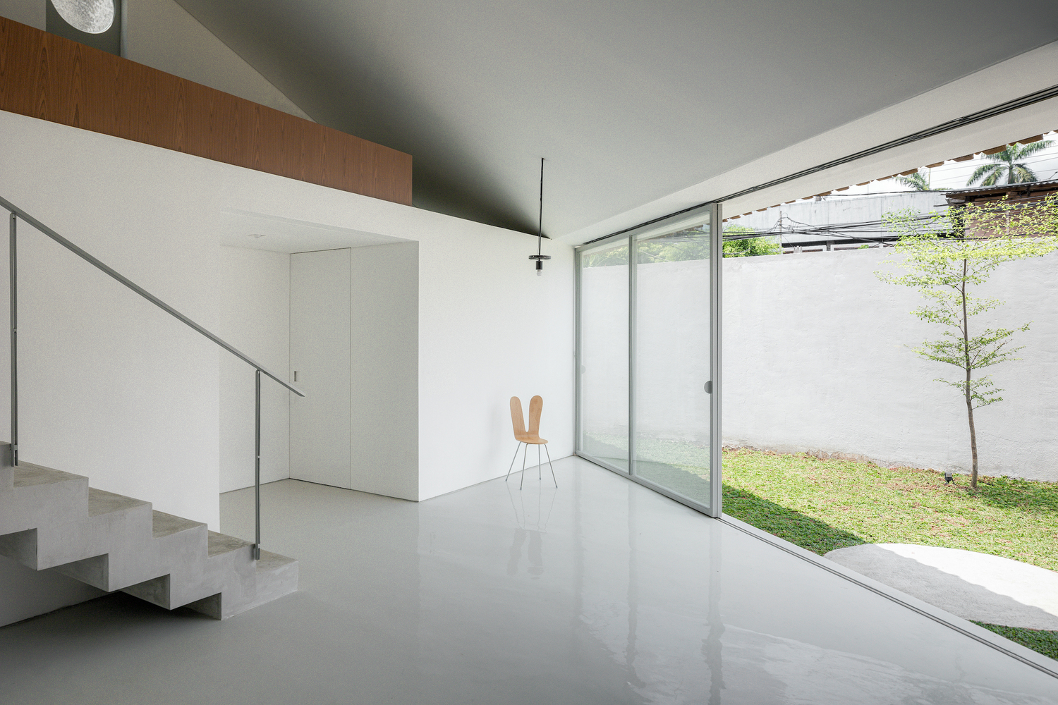Interior living space with polished floor, open staircase and full-height glazing to the garden