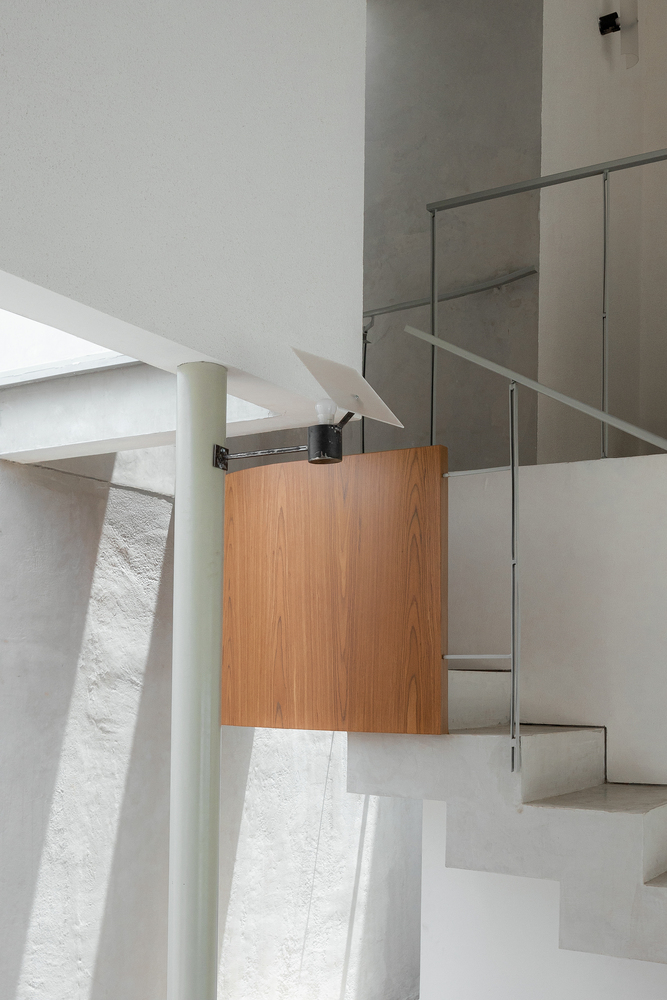 Stairwell detail showing timber cabinetry, glass railing and a cylindrical column under skylight