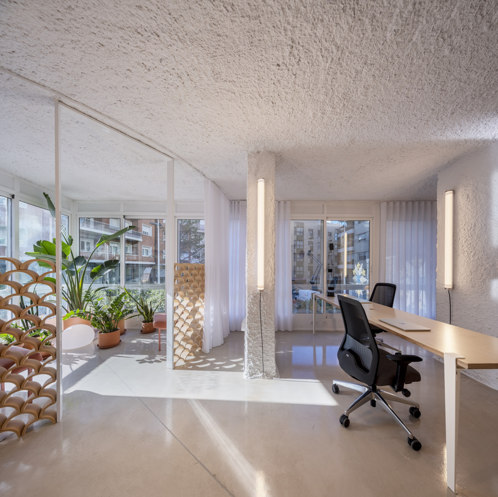 Workspace with embedded desk and potted plants on the balcony visible through sheer curtains
