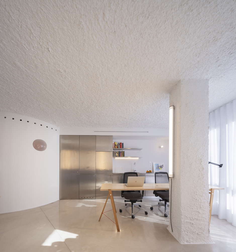 Workspace nook with brushed metal cabinetry and floating shelf under a vaulted sprayed ceiling