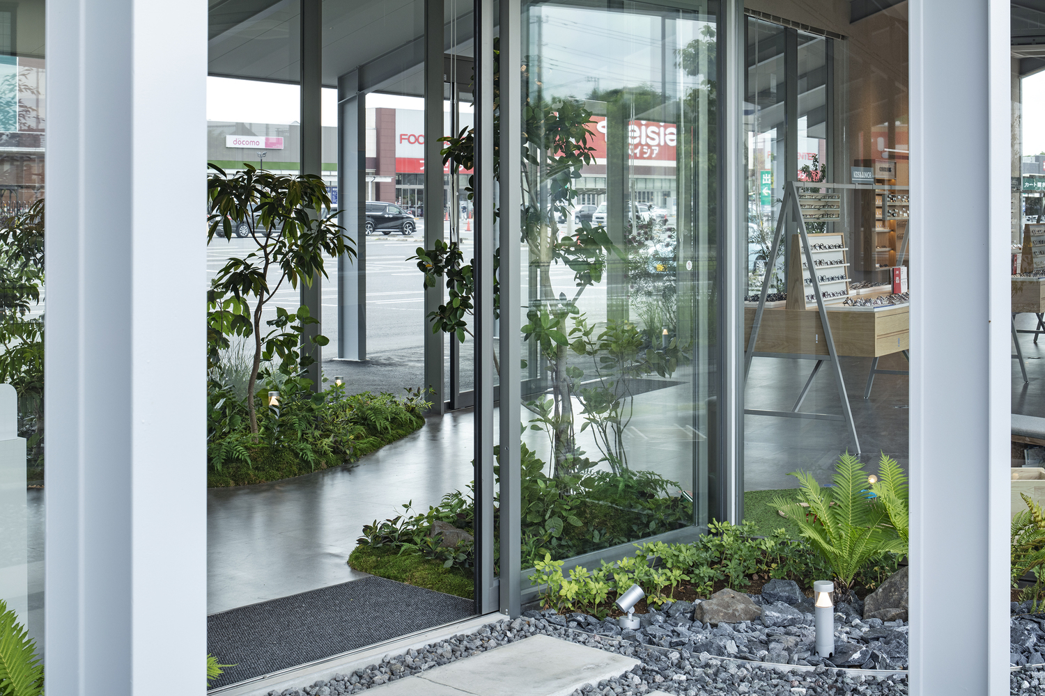 Interior planted beds with glass partitions and pebble ground cover beneath exposed structural ceiling