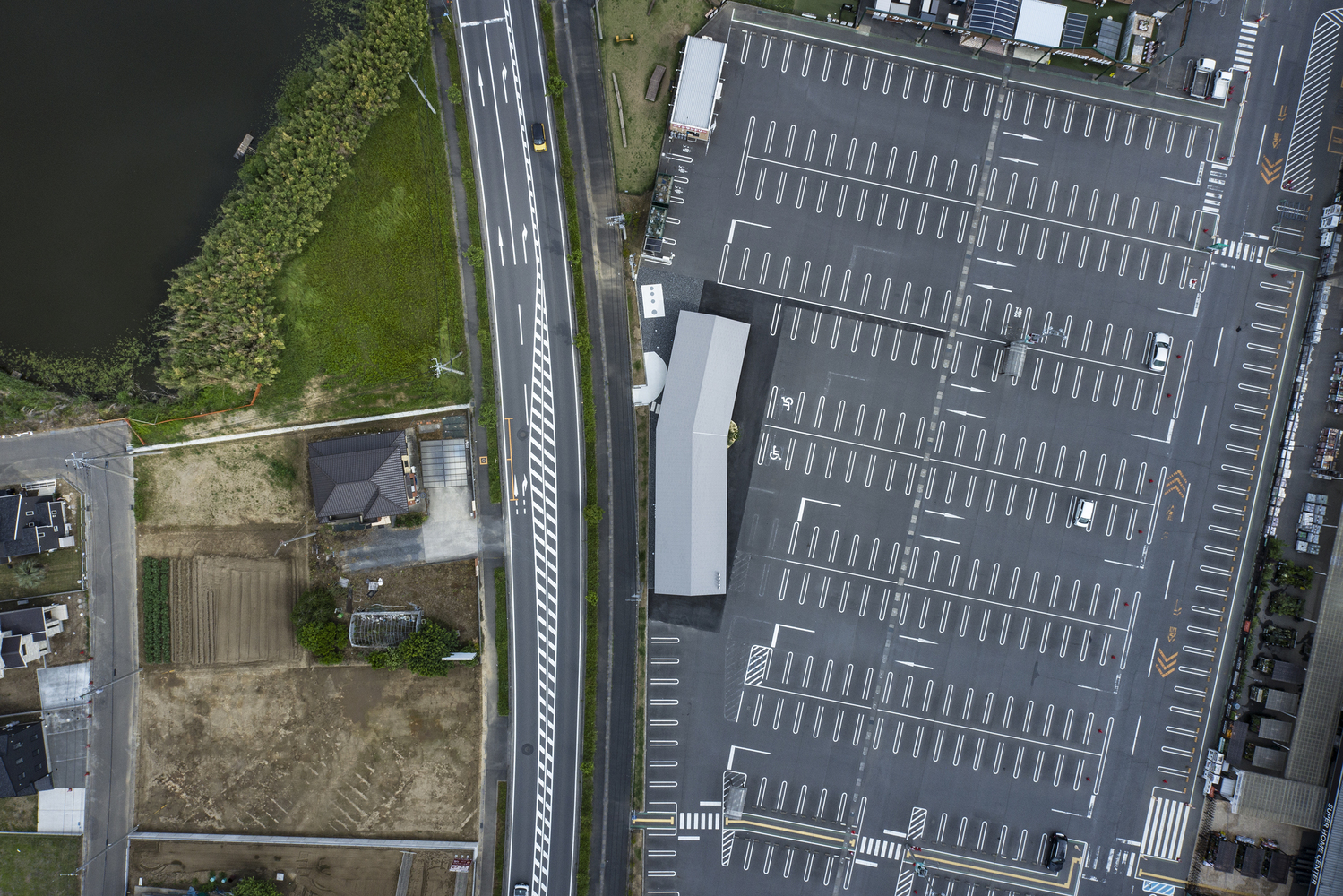 Aerial view of the parking lot with white striping and linear roof adjacent to roadway
