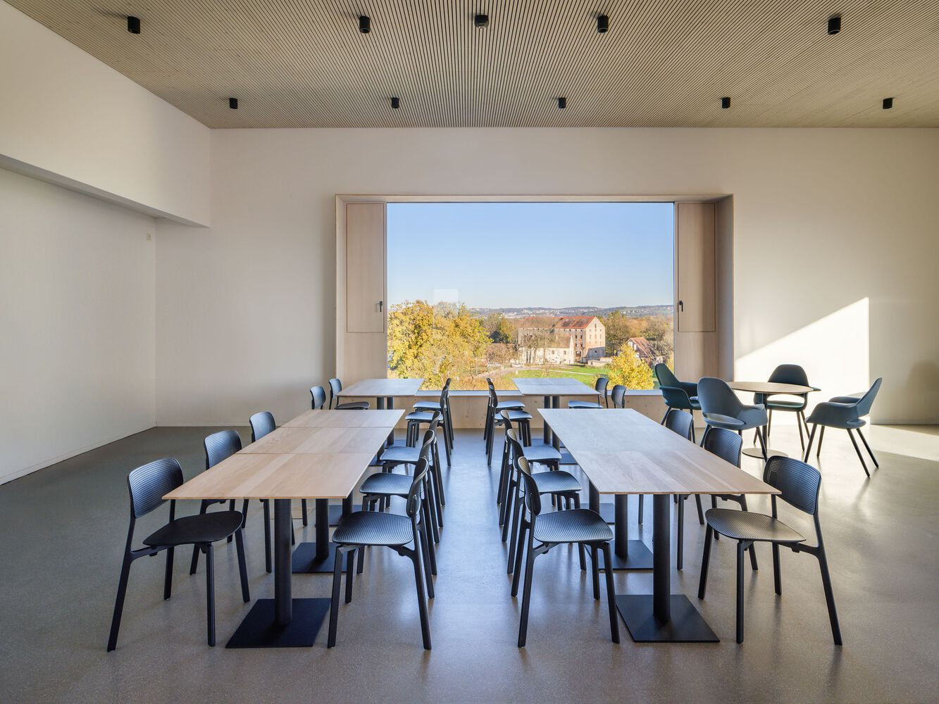 Conference tables arranged in a row beneath a timber slat ceiling with sunlight entering from the window