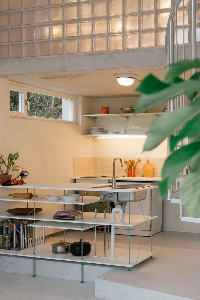 Freestanding metal kitchen island beneath a glass block mezzanine floor with houseplants in foreground