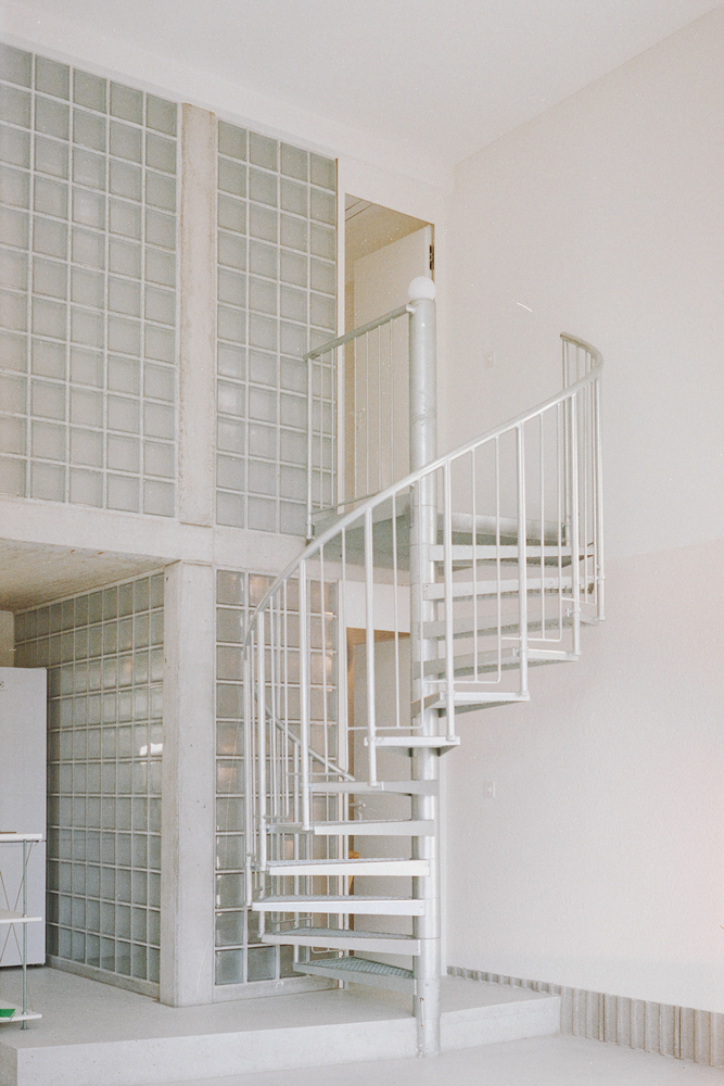 White spiral staircase connecting ground floor to glass block mezzanine level