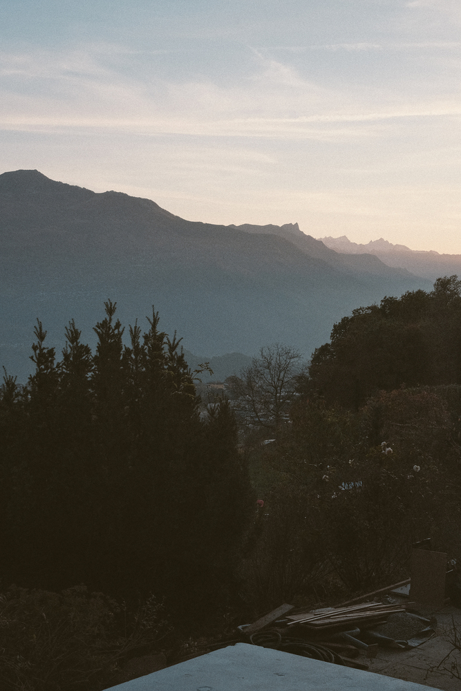 View across forested hillside toward distant mountain ridges at dusk