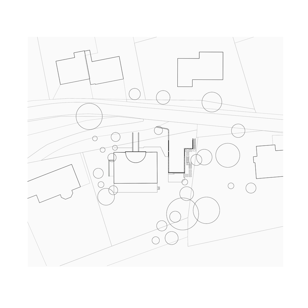 Site plan drawing showing building footprints, circular tree symbols and curved road among neighboring structures