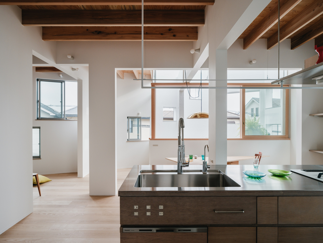 Kitchen island with stainless steel sink and glass transom windows framed in timber