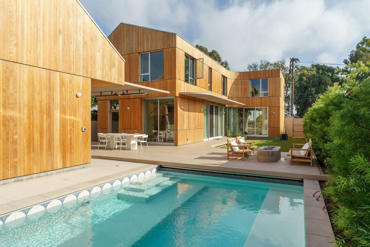 Rear facade with vertical timber cladding and swimming pool framed by mature trees