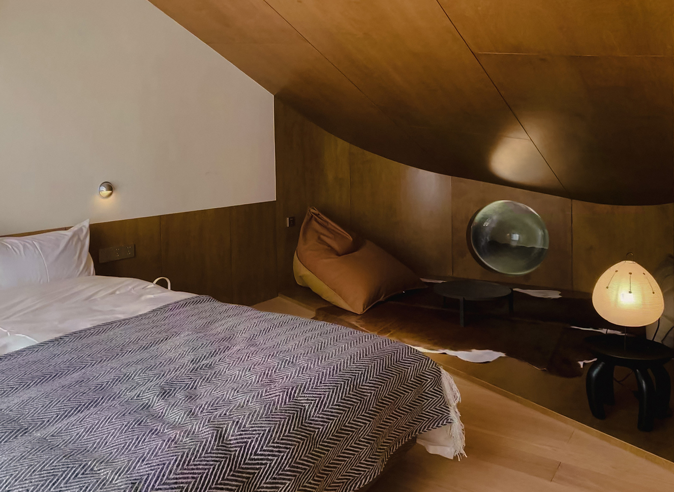 Bedroom with timber-paneled walls and ceiling beneath a curved plaster vault with warm lighting