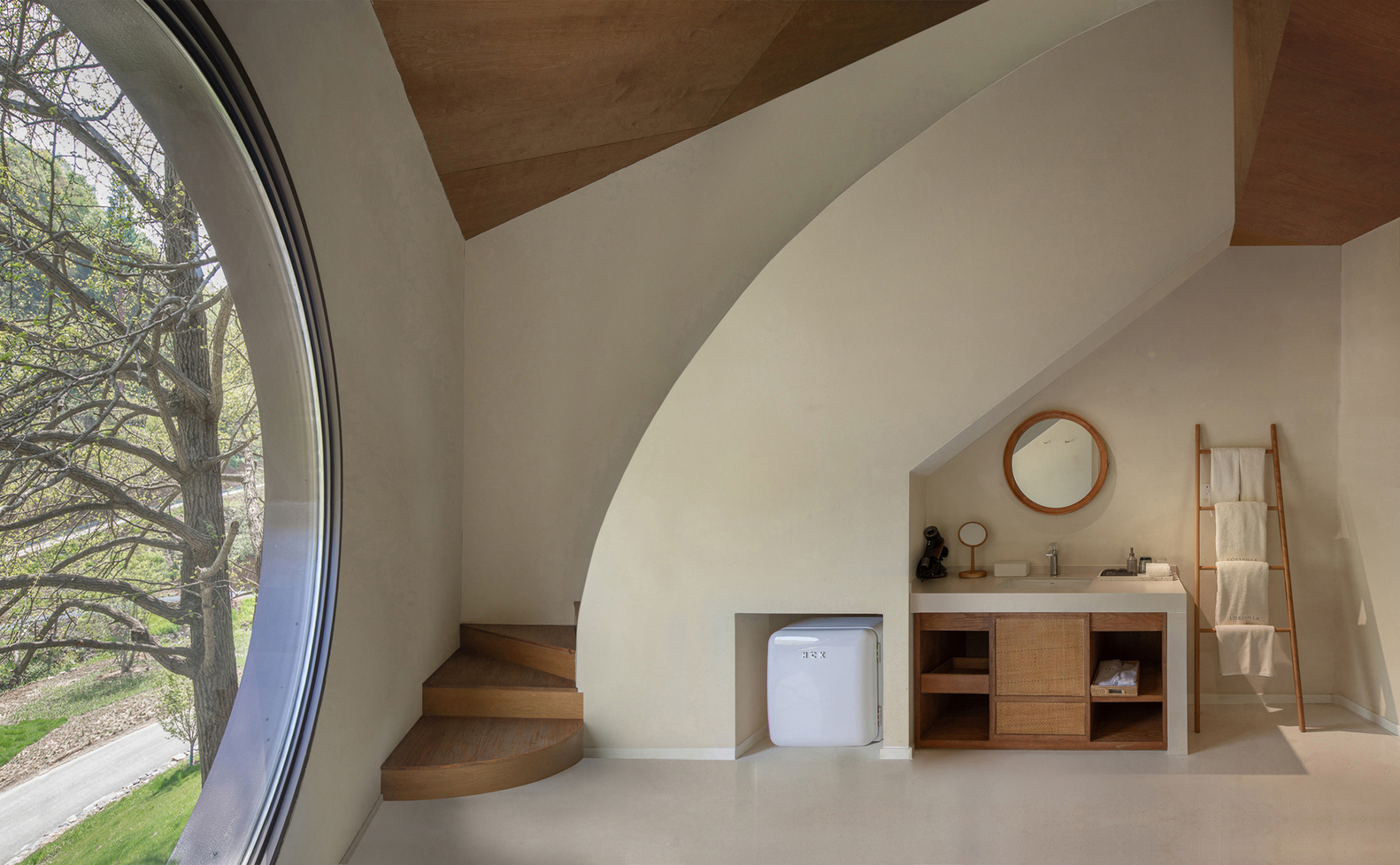 Bathroom with curved plaster stair, timber vanity unit, and floor-to-ceiling curved glass overlooking bare trees