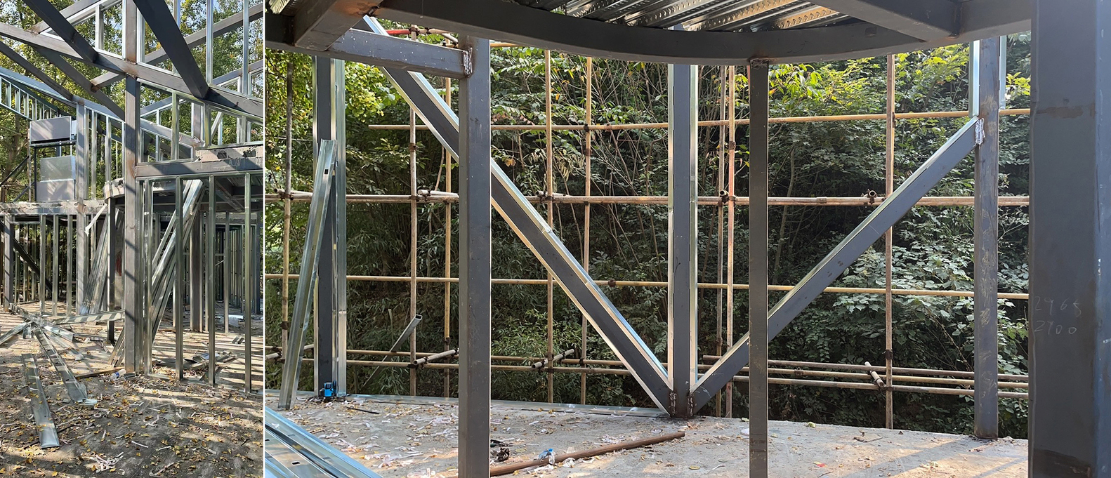 Steel structural frame under construction with diagonal bracing and forest visible beyond