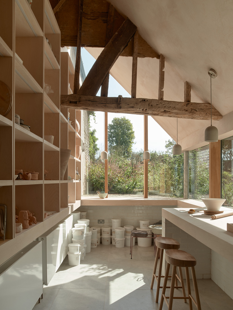 Interior workshop with exposed timber beams, plywood shelving and pendant lights above a counter with stools