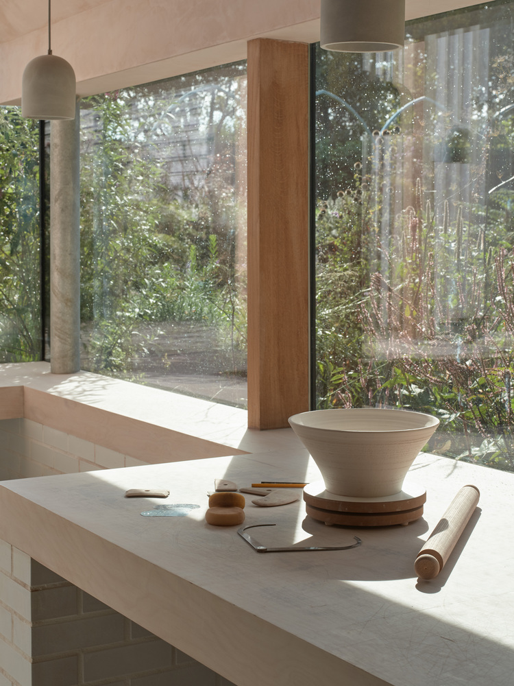 Kitchen counter with timber column and pendant light overlooking garden through floor-to-ceiling glazing