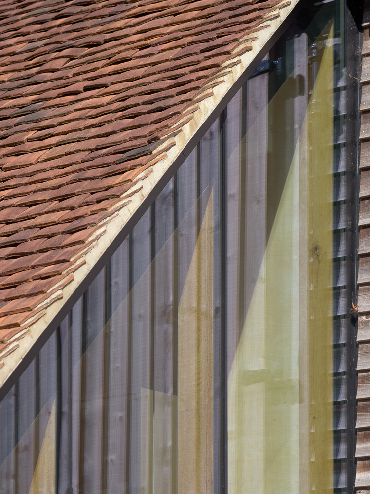 Glazed gable end with vertical timber framing beneath a clay tile roof slope