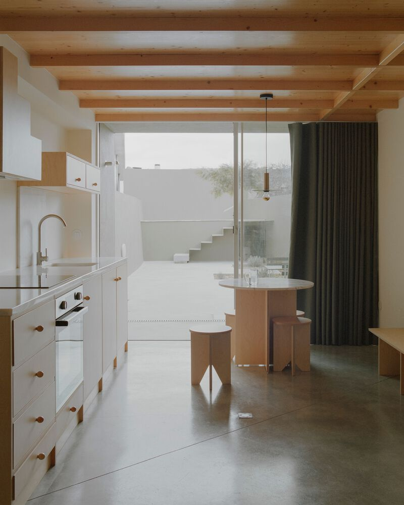 Kitchen and dining area with timber ceiling beams and view to exterior staircase through glazed wall