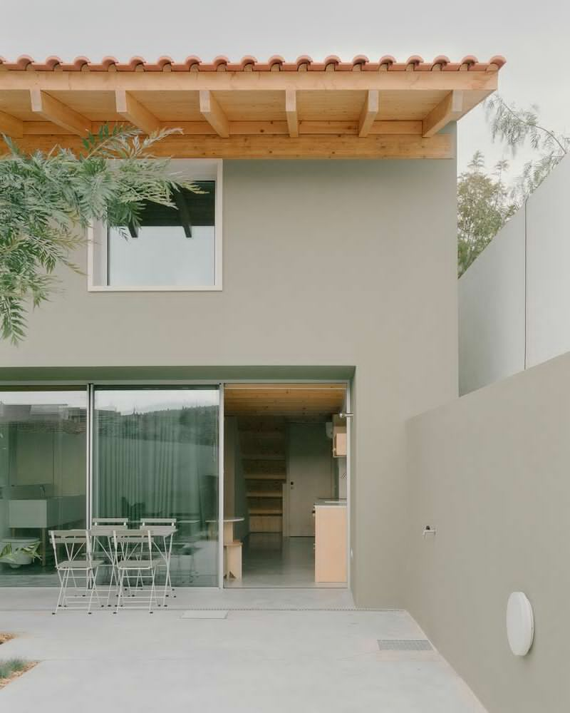 Rear courtyard with sliding glass doors, exposed timber eaves and overhanging tree branches