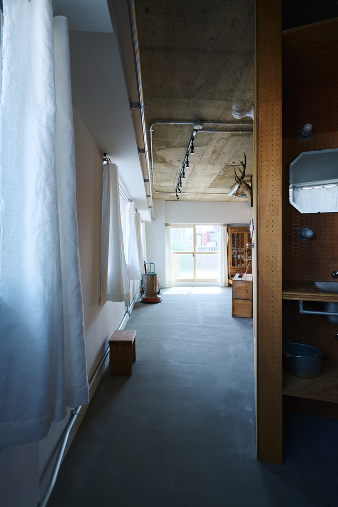 Corridor with grey curtains along white walls, exposed concrete ceiling, and polished concrete floor