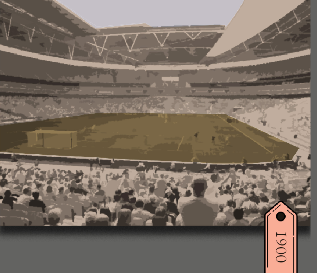 View from stadium seating toward a green playing field with spectators in the foreground