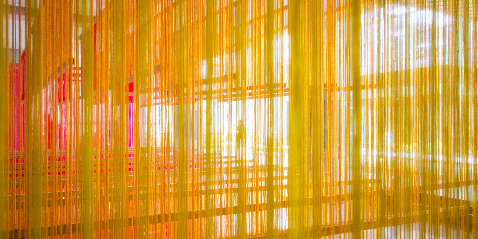 Close-up of the translucent yellow and orange strings filtering sunlight through the installation