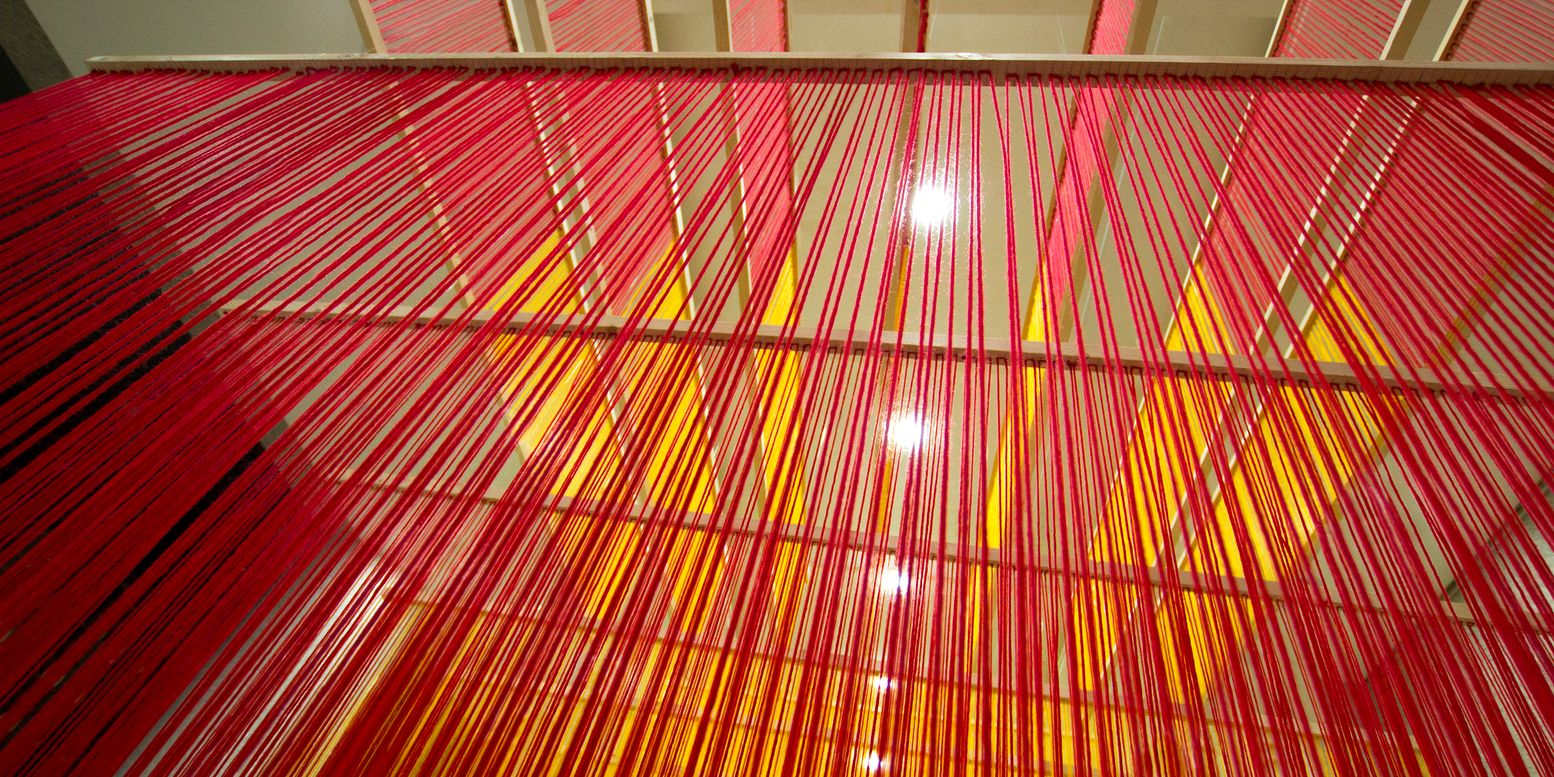 Upward view through layers of pink and orange thread with recessed ceiling lights visible above