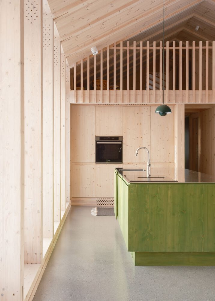 Kitchen detail showing green island, blonde plywood cabinetry and vertical timber slat screen above the gable wall